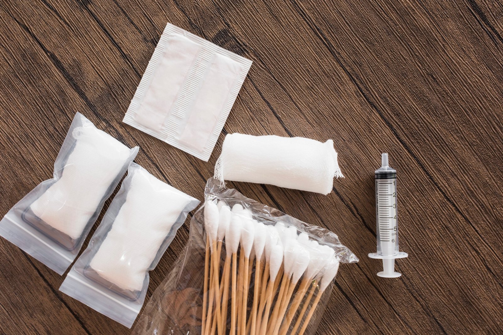 medical-cotton-gauze-bandage-syringe-pack-cotton-swab-wooden-table